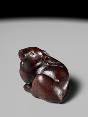 Lot 146 - MASANOBU: A NAGOYA SCHOOL WOOD NETSUKE OF A HARE WITH AMBER EYES