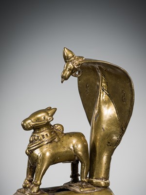 Lot 289 - A BRASS FIGURE OF NANDI CANOPIED BY A CROWNED NAGA, INDIA, 17TH CENTURY