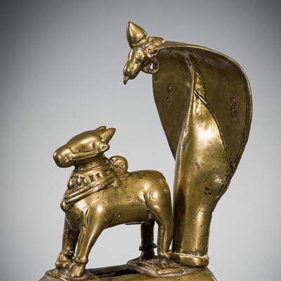 Lot 289 - A BRASS FIGURE OF NANDI CANOPIED BY A CROWNED NAGA, INDIA, 17TH CENTURY