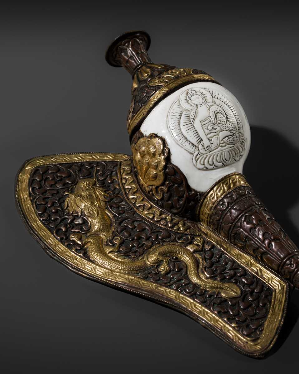 Lot 29 - A CARVED CONCH-SHELL TRUMPET, DUNG DKAR, WITH PARCEL-GILT COPPER REPOUSSÉ MOUNT