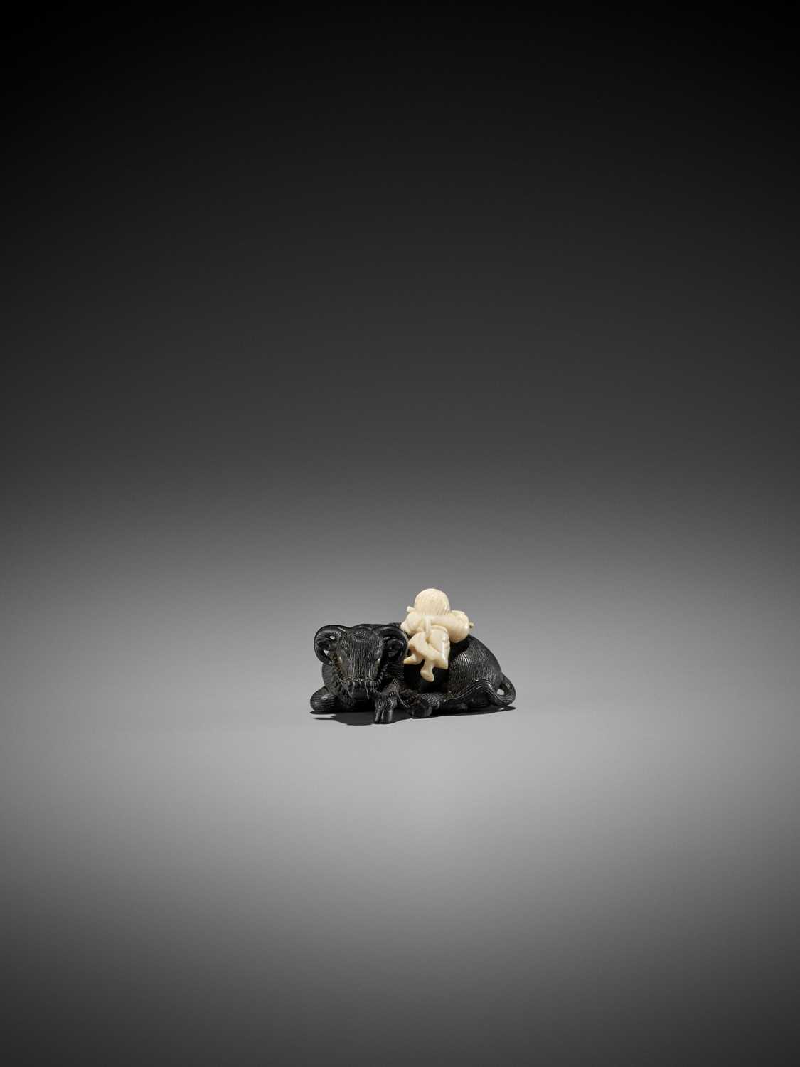 Lot 158 - KAGETOSHI: AN EXQUISITE EBONY WOOD AND IVORY NETSUKE OF AN OX WITH BOKUDO