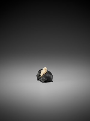 Lot 158 - KAGETOSHI: AN EXQUISITE EBONY WOOD AND IVORY NETSUKE OF AN OX WITH BOKUDO