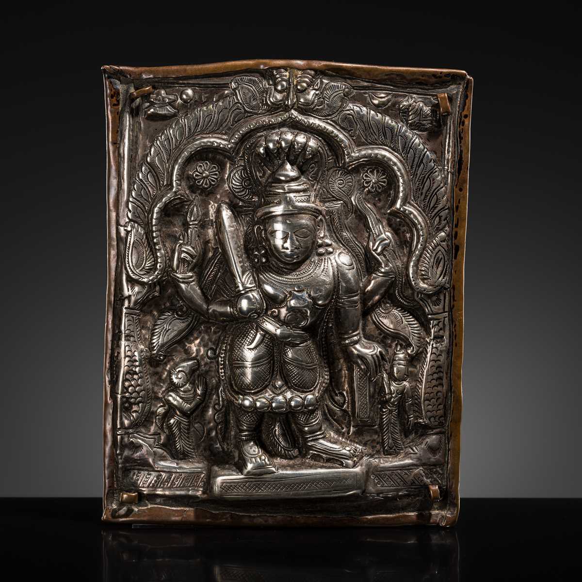 Lot 107 - A COPPER CEREMONIAL SHIELD WITH SILVER REPOUSSÉ PLAQUE DEPICTING VIRABHADRA, INDIA, 19TH CENTURY