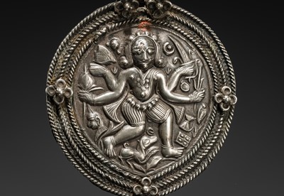 Lot 108 - A SILVER REPOUSSÉ AMULET IN THE SHAPE OF A PIPAL LEAF DEPICTING THE DANCING SHIVA BHAIRAVA, AJMER, 19TH CENTURY