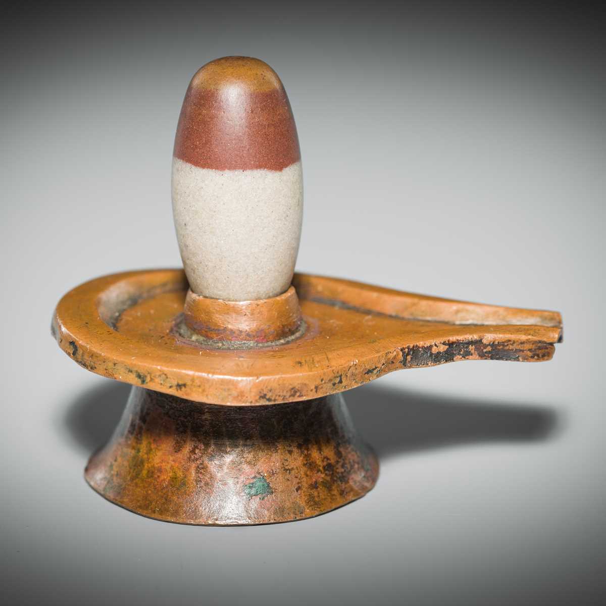 Lot 187 - A NARMADA RIVER STONE LINGAM AND COPPER YONI, 19TH CENTURY OR EARLIER