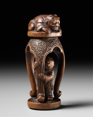 Lot 481 - GYOKUSEN: A PLAYFUL WOOD NETSUKE OF A KARAKO HIDING UNDER A TABLE, MITATE OF SHOKI AND ONI