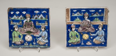 Lot 2183 - A PAIR OF MOLDED QAJAR ‘COURTIERS AT A PICNIC’ TILES