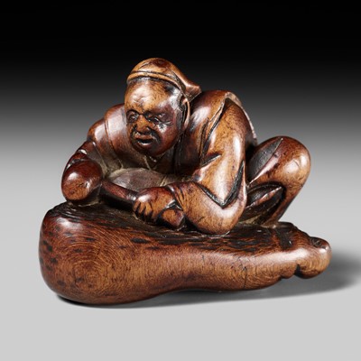 Lot 490 - HOSHUNSAI MASAYUKI: A FINE WOOD NETSUKE OF A CARVER CHISELING A GIANT FOOT