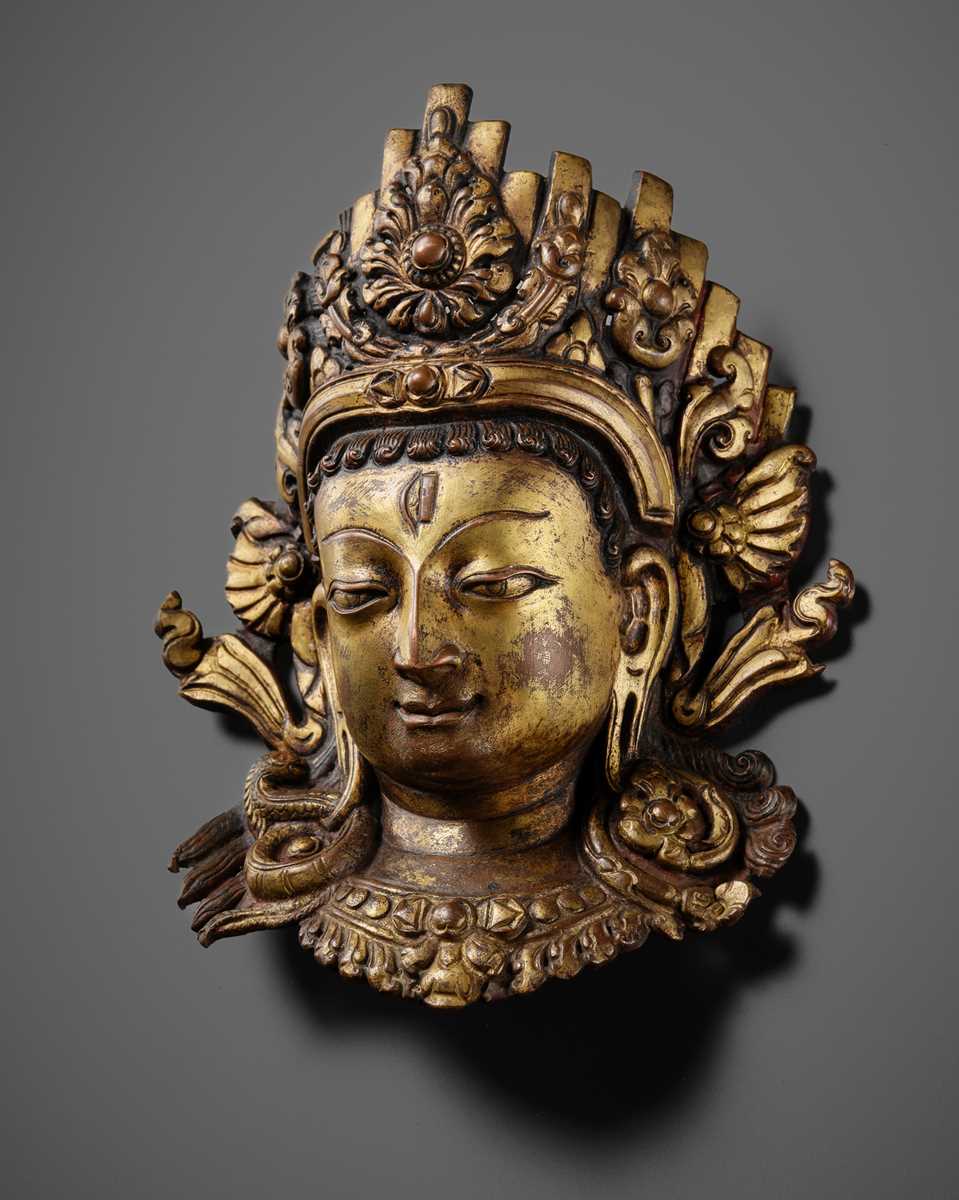 Lot 312 - A GILT-COPPER REPOUSSÉ LINGA COVER WITH THE FACE OF SHIVA, MALLA PERIOD, NEPAL, 15TH-16TH CENTURY