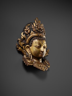 Lot 312 - A GILT-COPPER REPOUSSÉ LINGA COVER WITH THE FACE OF SHIVA, MALLA PERIOD, NEPAL, 15TH-16TH CENTURY