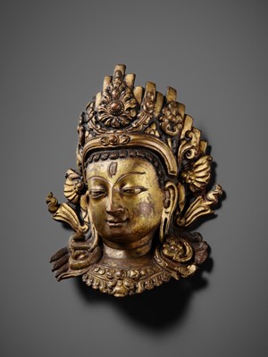 Lot 312 - A GILT-COPPER REPOUSSÉ LINGA COVER WITH THE FACE OF SHIVA, MALLA PERIOD, NEPAL, 15TH-16TH CENTURY