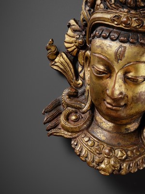 Lot 312 - A GILT-COPPER REPOUSSÉ LINGA COVER WITH THE FACE OF SHIVA, MALLA PERIOD, NEPAL, 15TH-16TH CENTURY