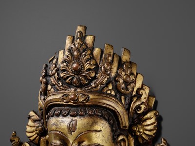 Lot 312 - A GILT-COPPER REPOUSSÉ LINGA COVER WITH THE FACE OF SHIVA, MALLA PERIOD, NEPAL, 15TH-16TH CENTURY