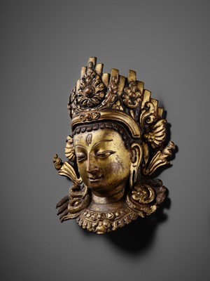 Lot 312 - A GILT-COPPER REPOUSSÉ LINGA COVER WITH THE FACE OF SHIVA, MALLA PERIOD, NEPAL, 15TH-16TH CENTURY