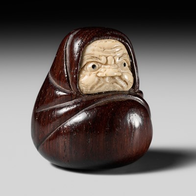 Lot 498 - DORAKU: AN AMUSING INLAID WOOD NETSUKE OF A DARUMA DOLL