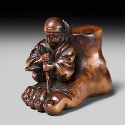 Lot 230 - HOSHUNSAI MASAYUKI: A FINE WOOD NETSUKE OF A CARVER CHISELING A GIANT FOOT