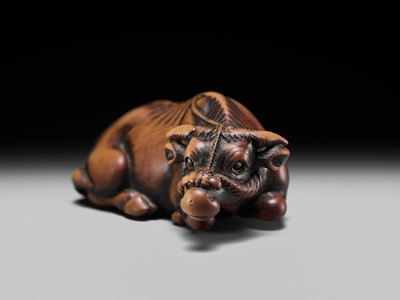 Lot 147 - A SUPERB WOOD NETSUKE OF A RECUMBENT OX, ATTRIBUTED TO OKATOMO