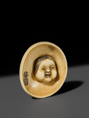 Lot 143 - MITSUHIRO: AN IVORY NETSUKE OF AN OKAME MASK INSIDE AN EARTHENWARE BOWL, DATED 1840