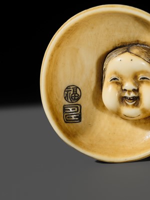 Lot 143 - MITSUHIRO: AN IVORY NETSUKE OF AN OKAME MASK INSIDE AN EARTHENWARE BOWL, DATED 1840