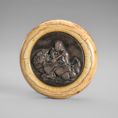 Lot 1709 - A FINE IVORY AND SHIBUICHI KAGAMIBUTA NETSUKE OF A RAKAN WITH SHISHI