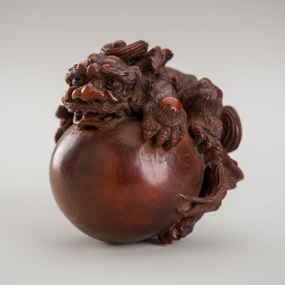 Lot 1288 - A WOOD NETSUKE OF A SHISHI ON A LARGE BALL