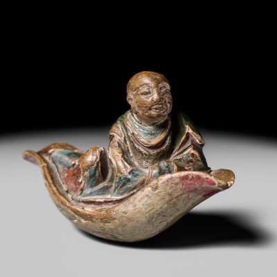 Lot 63 - A RARE SAISHIKI NETSUKE OF A MONK ON A LOTUS BOAT, STYLE OF YOSHIMURA SHUZAN