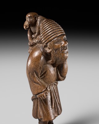 Lot 200 - AN UNUSUAL WOOD NETSUKE OF A FOREIGN SARUMAWASHI (MONKEY TRAINER)