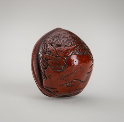 Lot 1202 - A KURUMI (WALNUT) NETSUKE DEPICTING A HARE PRANCING OVER WAVES