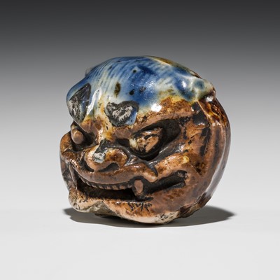 Lot 535 - A HIRADO GLAZED PORCELAIN MASK NETSUKE OF AN ONI