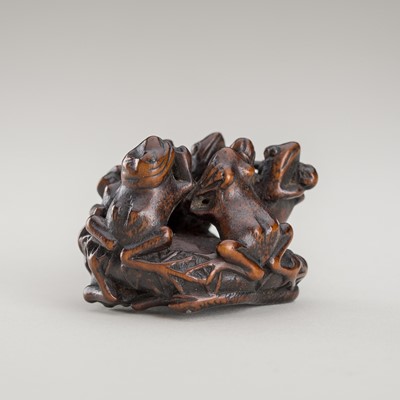 Lot 1379 - A FINE WOOD NETSUKE OF A GROUP OF FROGS ON A LOTUS LEAF