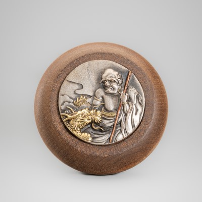 A PAULOWNIA AND MIXED METAL KAGAMIBUTA NETSUKE OF THE RAKAN HANDAKA SONJA