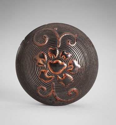 Lot 1758 - A LACQUERED WOOD MANJU NETSUKE WITH PEONY SCROLLS