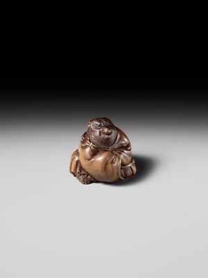 Lot 243 - A FINE AND HUMOROUS WOOD NETSUKE OF TANUKI DISGUISED AS A PRIEST