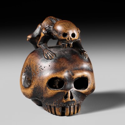 Lot 469 - A WOOD NETSUKE OF A SKELETON ON A GIANT SKULL