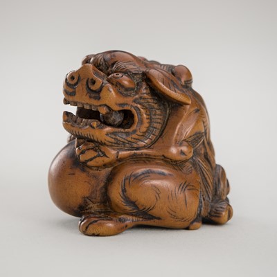 A WOOD NETSUKE OF A SHISHI WITH BALL