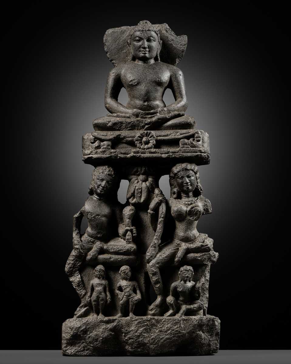 Lot 334 - A BLACK STONE STELE DEPICTING AN ENTHRONED MAHAVIRA ATTENDED BY A YAKSHA AND YAKSHI, PALA PERIOD, 11TH-12TH CENTURY