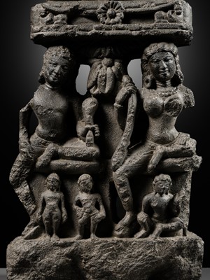 Lot 334 - A BLACK STONE STELE DEPICTING AN ENTHRONED MAHAVIRA ATTENDED BY A YAKSHA AND YAKSHI, PALA PERIOD, 11TH-12TH CENTURY
