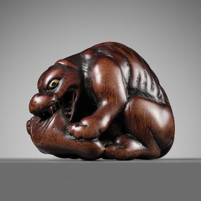 Lot 134 - MINKO: A FINE WOOD NETSUKE OF A VORACIOUS WOLF WITH VENISON HAUNCH