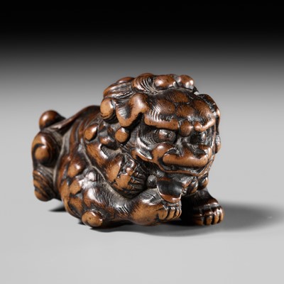 Lot 87 - A SUPERB WOOD NETSUKE OF A SHISHI GROOMING ITSELF, CIRCLE OF RISUKE GARAKU