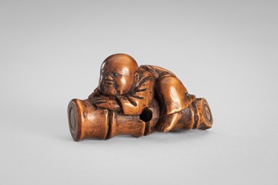 Lot 349 - A WOOD NETSUKE OF A BOY ON A BAMBOO LOG
