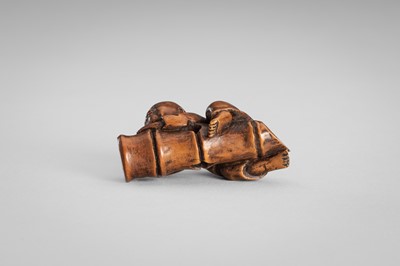 Lot 349 - A WOOD NETSUKE OF A BOY ON A BAMBOO LOG