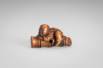 Lot 349 - A WOOD NETSUKE OF A BOY ON A BAMBOO LOG