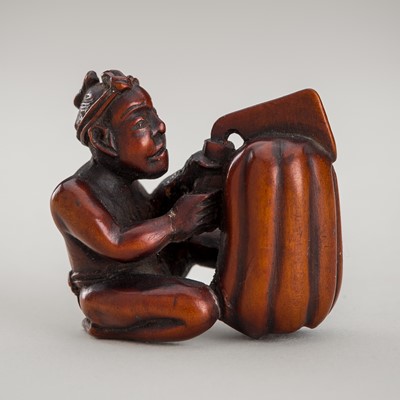 Lot 1392 - A WOOD NETSUKE OF A OF MAN CUTTING A LARGE PUMPKIN