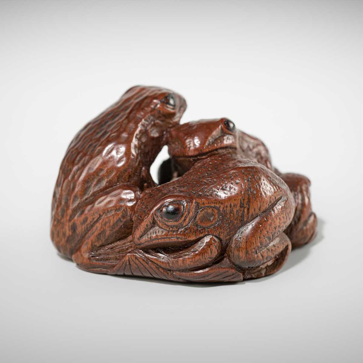 Lot 381 - SENKO: A WOOD NETSUKE OF FROGS AND LOTUS
