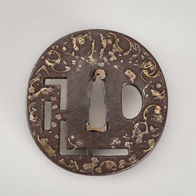 Lot 1504 - AN IRON SUKASHI TSUBA WITH GILT ORNAMENTAL DESIGN