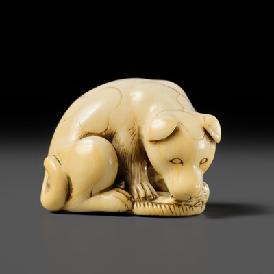 Lot 92 - A KYOTO SCHOOL IVORY NETSUKE OF A DOG PLAYING WITH A STRAW SANDAL