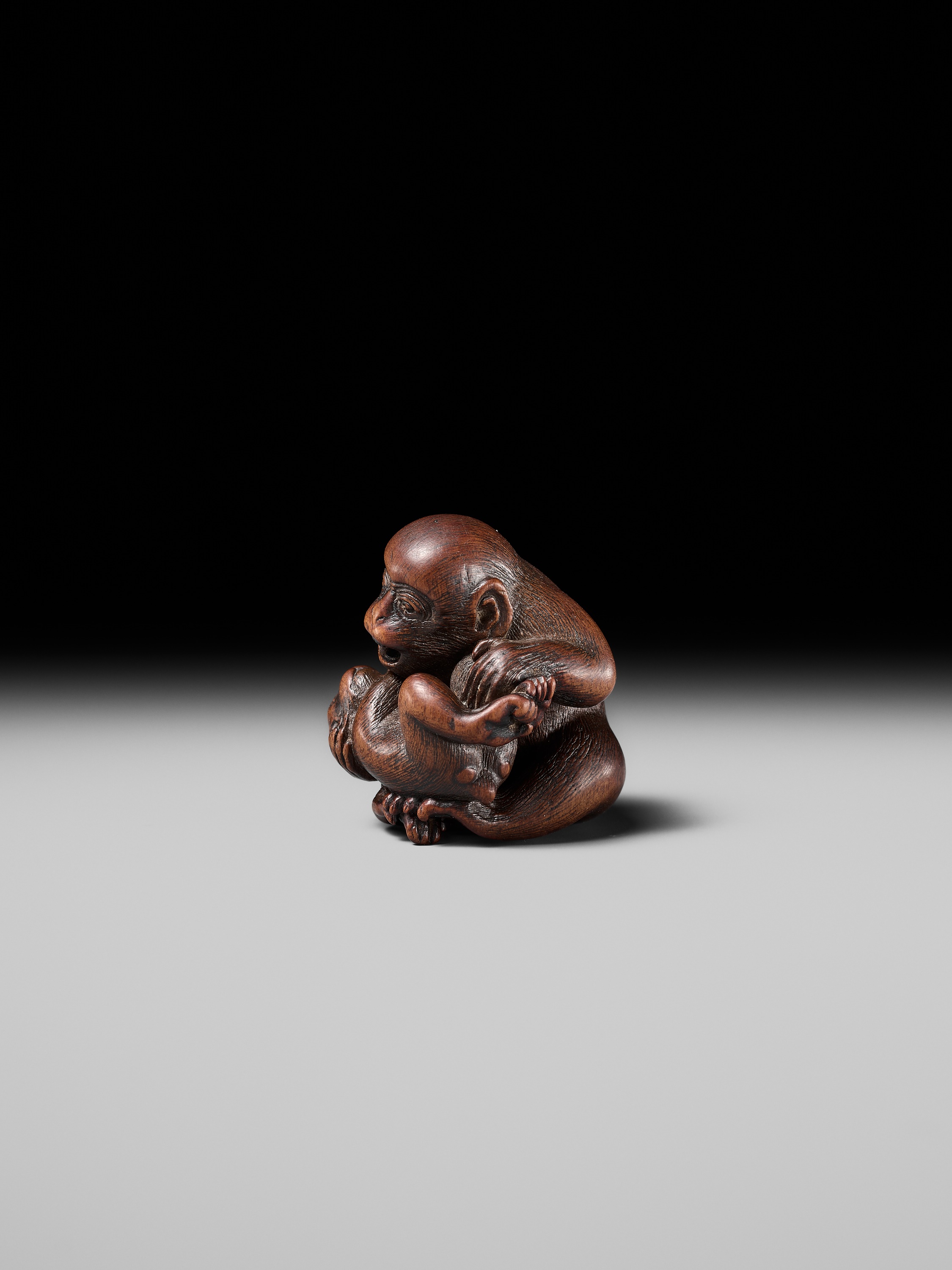Lot 114 - MASANAO: A SUPERB WOOD NETSUKE OF A MONKEY