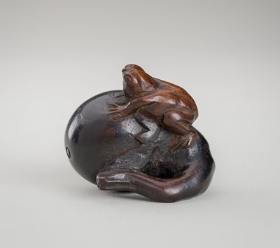 Lot 1289 - A WOOD NETSUKE OF A FROG ON A NASUBI (EGGPLANT)