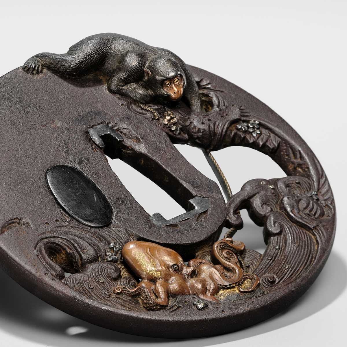 Lot 62 - AN INGENIOUS TETSUGENDO SCHOOL IRON TSUBA WITH A MONKEY CATCHING AN OCTOPUS