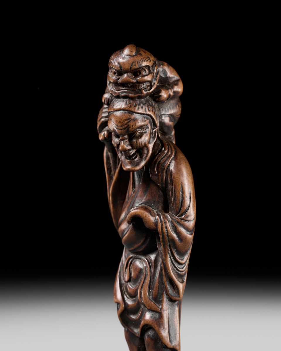 Lot 100 - A RARE WOOD NETSUKE OF A CHINESE IMMORTAL WITH AN ONI